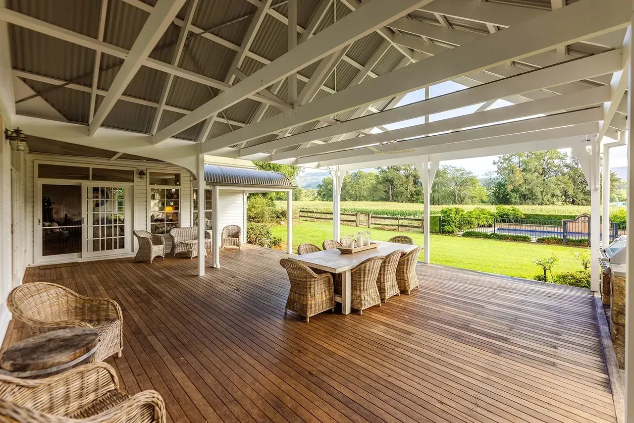 Wooden Deck With Wicker Furniture, Dining Table, Overlooking a Green Field — Stark Building & Constructions In Berry, NSW 