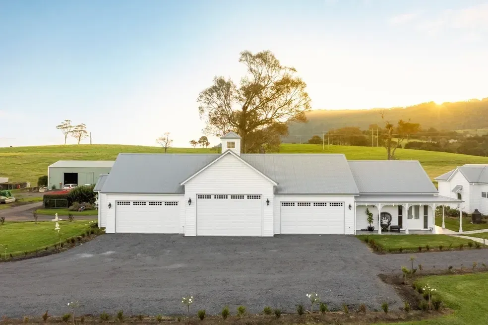 White Farmhouse With Three Garage Doors on a Gravel Driveway — Stark Building & Constructions In Berry, NSW