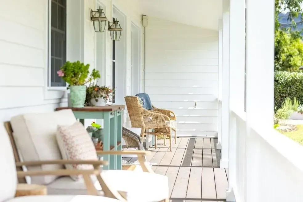 White Porch With Wooden Floors, Wicker Chairs, Table With Plants, and Classic Lanterns — Stark Building & Constructions In Berry, NSW