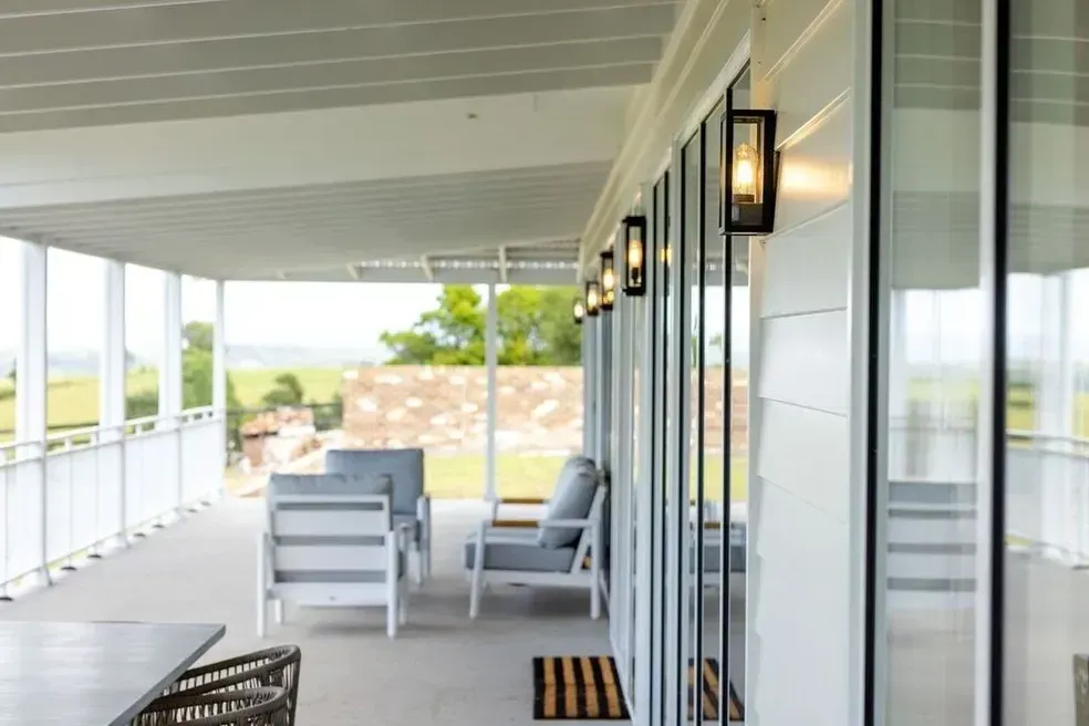 White Porch With Gray Furniture, Glass Doors, and Outdoor Lights Overlooking a Green Landscape — Stark Building & Constructions In Berry, NSW