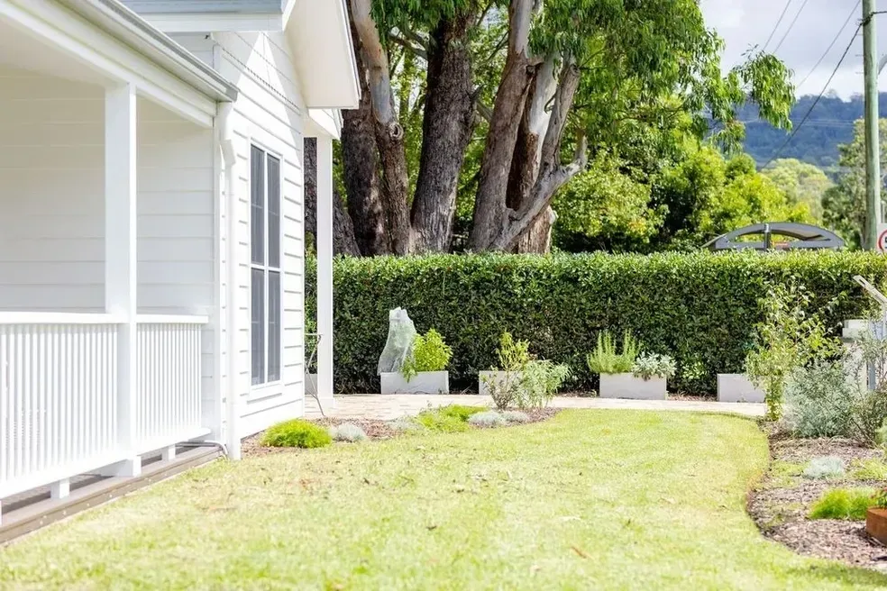 White House With Porch, Lush Green Lawn, Hedge and Trees in the Background — Stark Building & Constructions In Berry, NSW