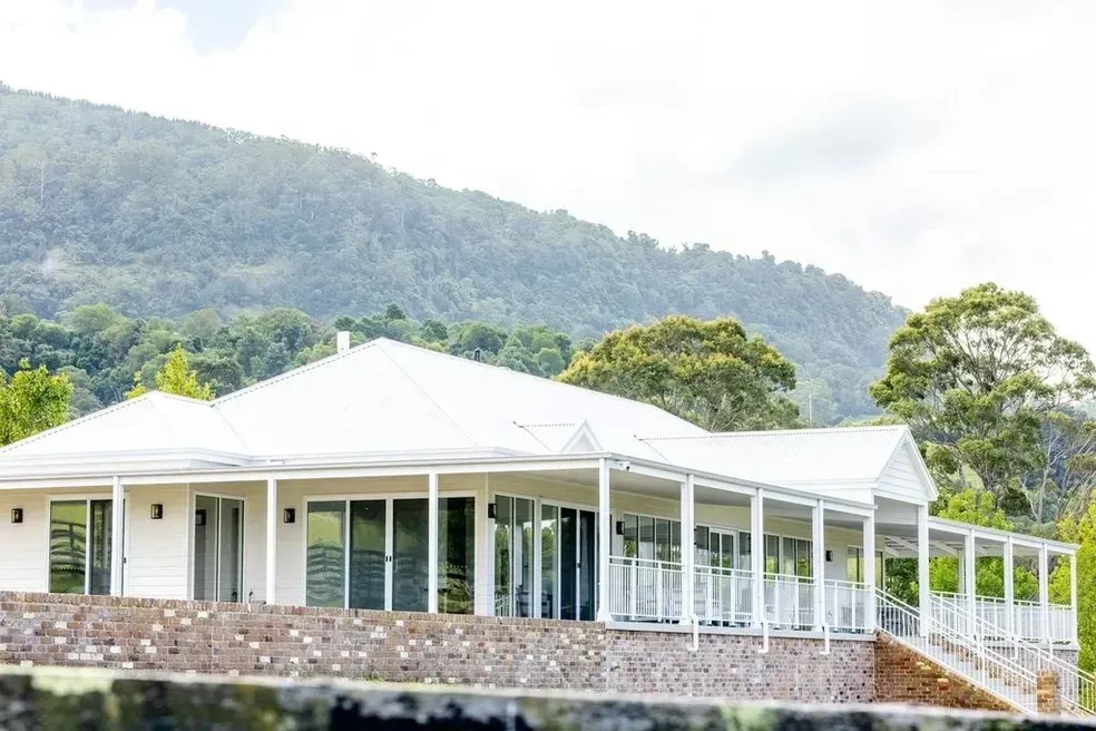 White House With Long Porch, Stone Base, Against a Mountain Backdrop — Stark Building & Constructions In Berry, NSW