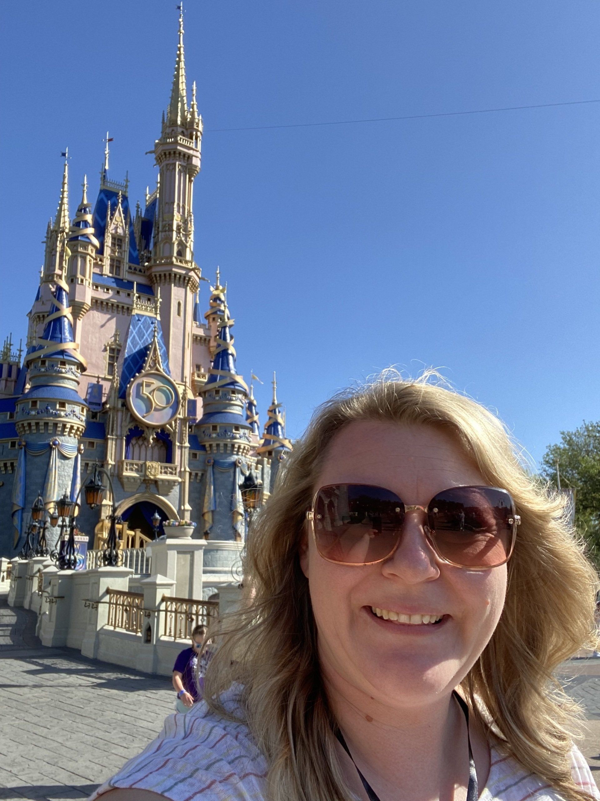 a woman wearing sunglasses is taking a selfie in front of a castle .