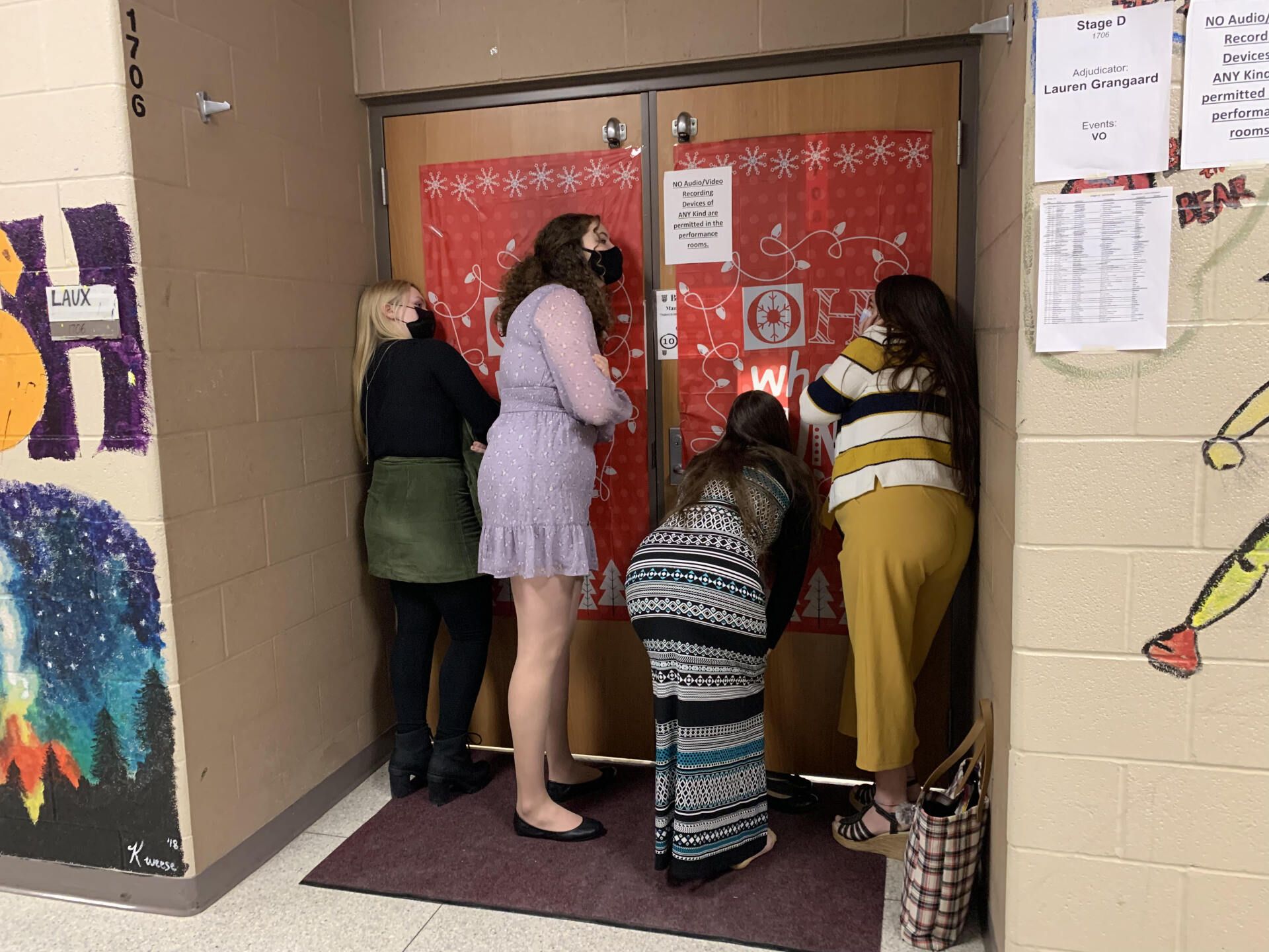 a group of women are standing in front of a door in a hallway .