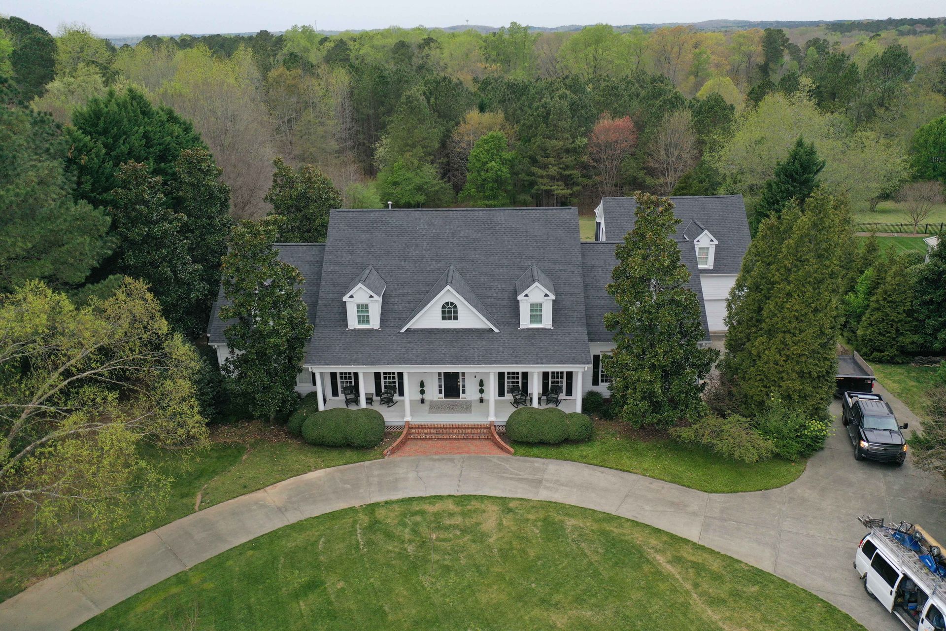 An aerial view of a large white house surrounded by trees.