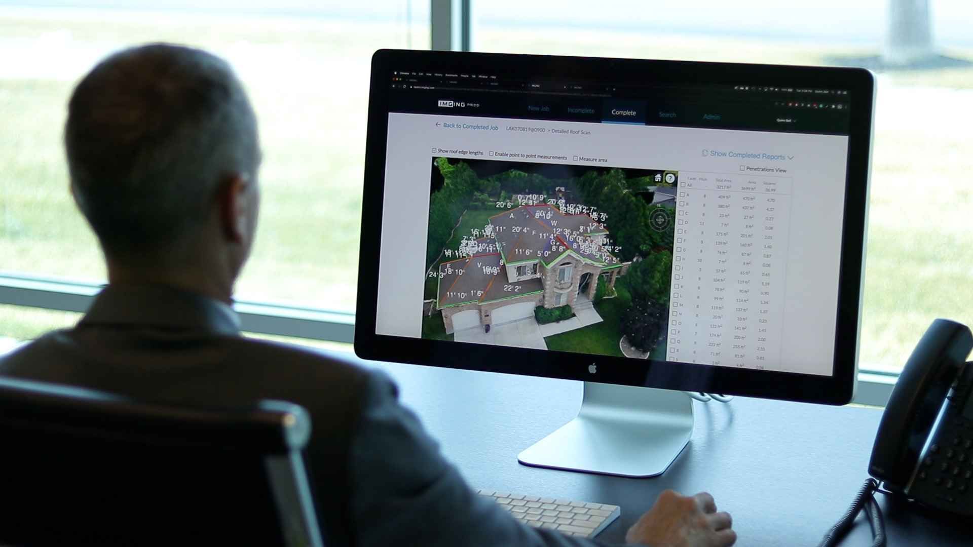 A man is sitting at a desk looking at a computer screen.
