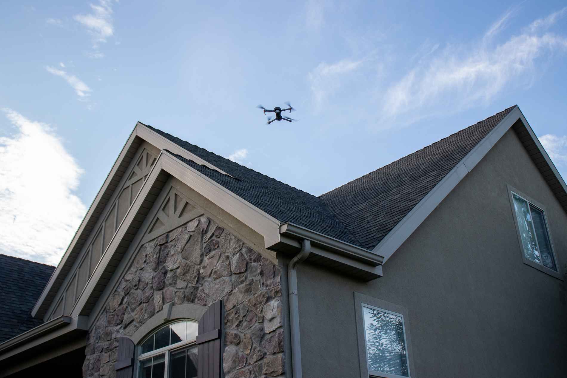 A drone is flying over the roof of a house.