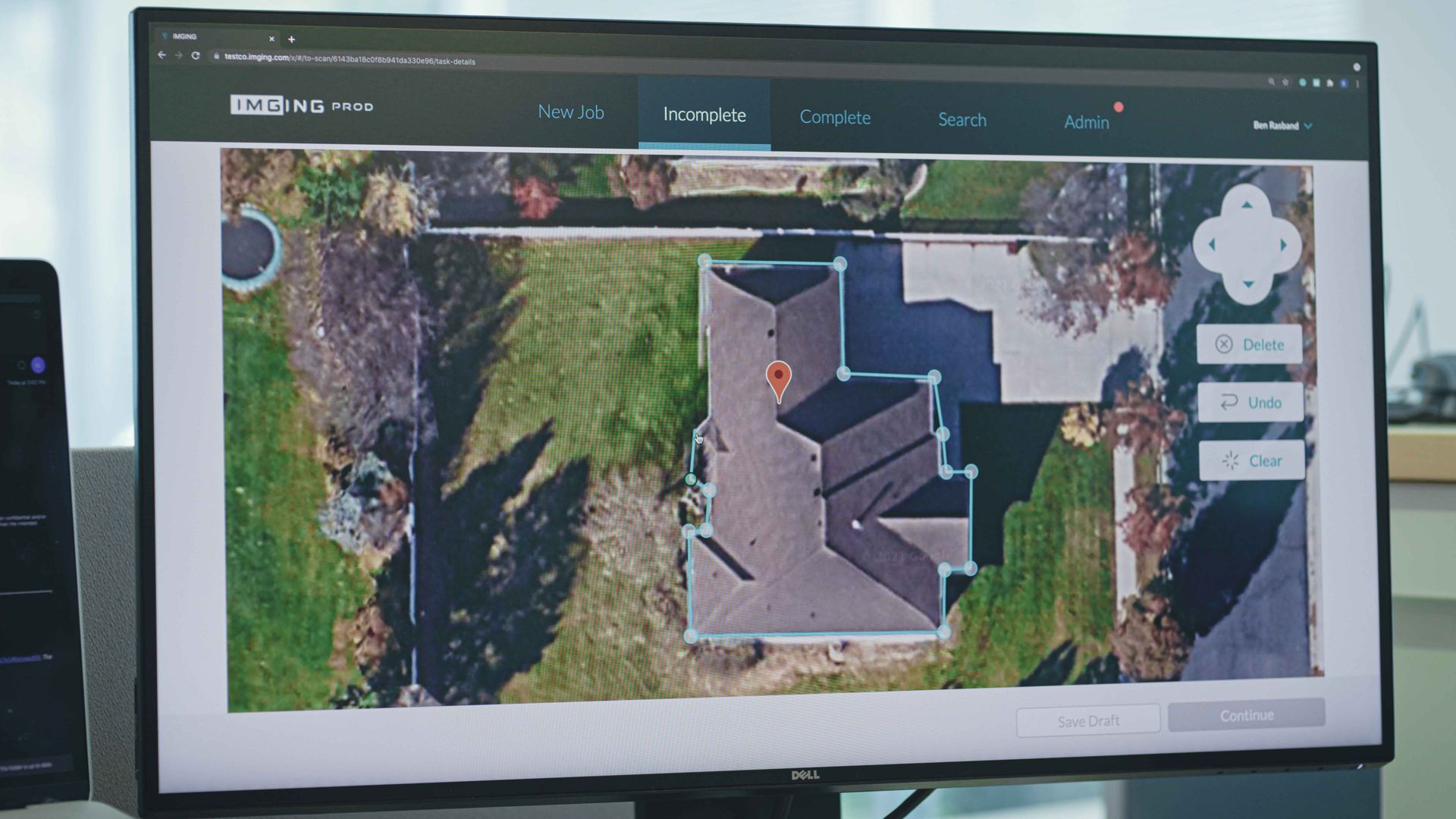 A computer monitor shows an aerial view of a house.