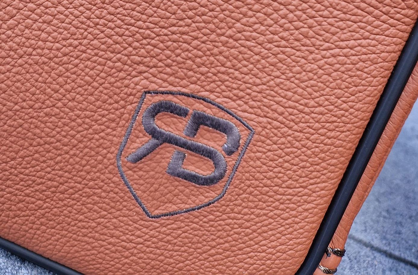 Een close-up van een bruine leren tas met een logo erop.