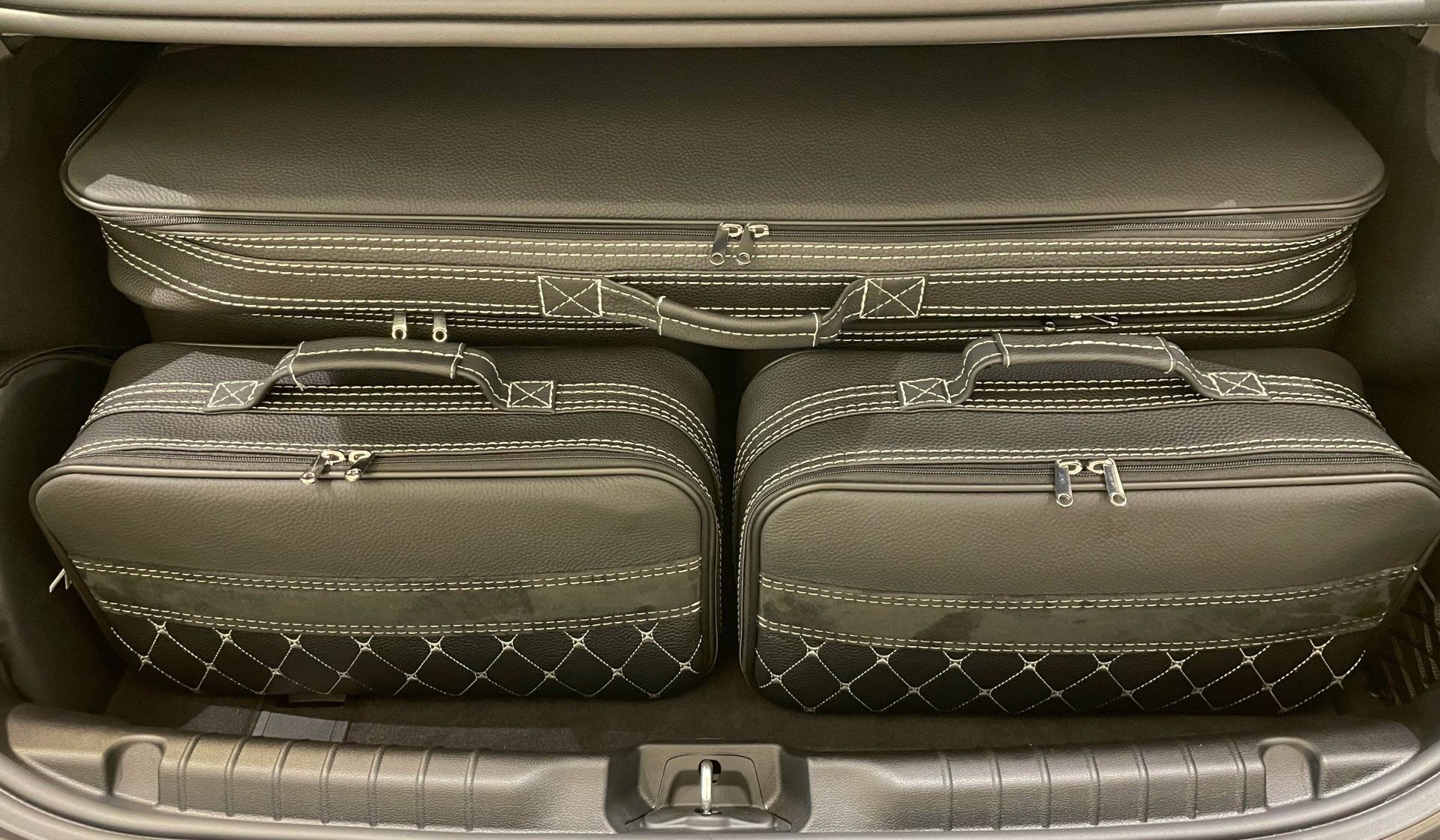 De kofferbak van een auto gevuld met bagage en een laptop