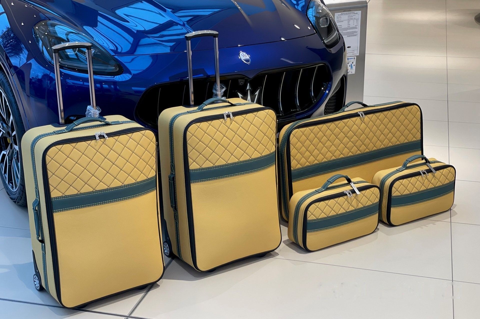 Een set bagage staat voor een blauwe auto.