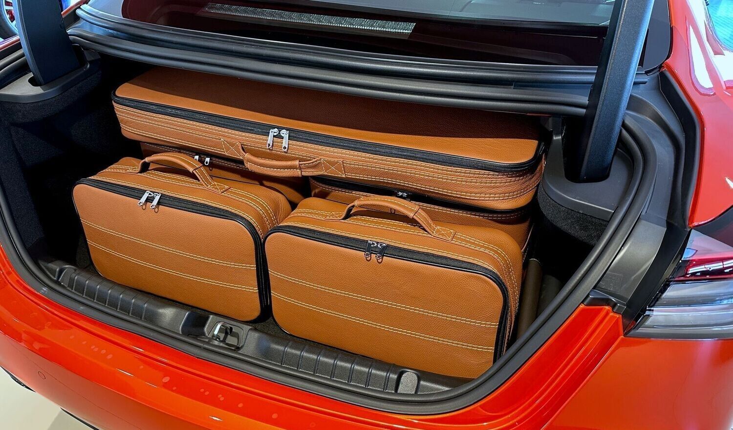De kofferbak van een rode auto is gevuld met bagage.