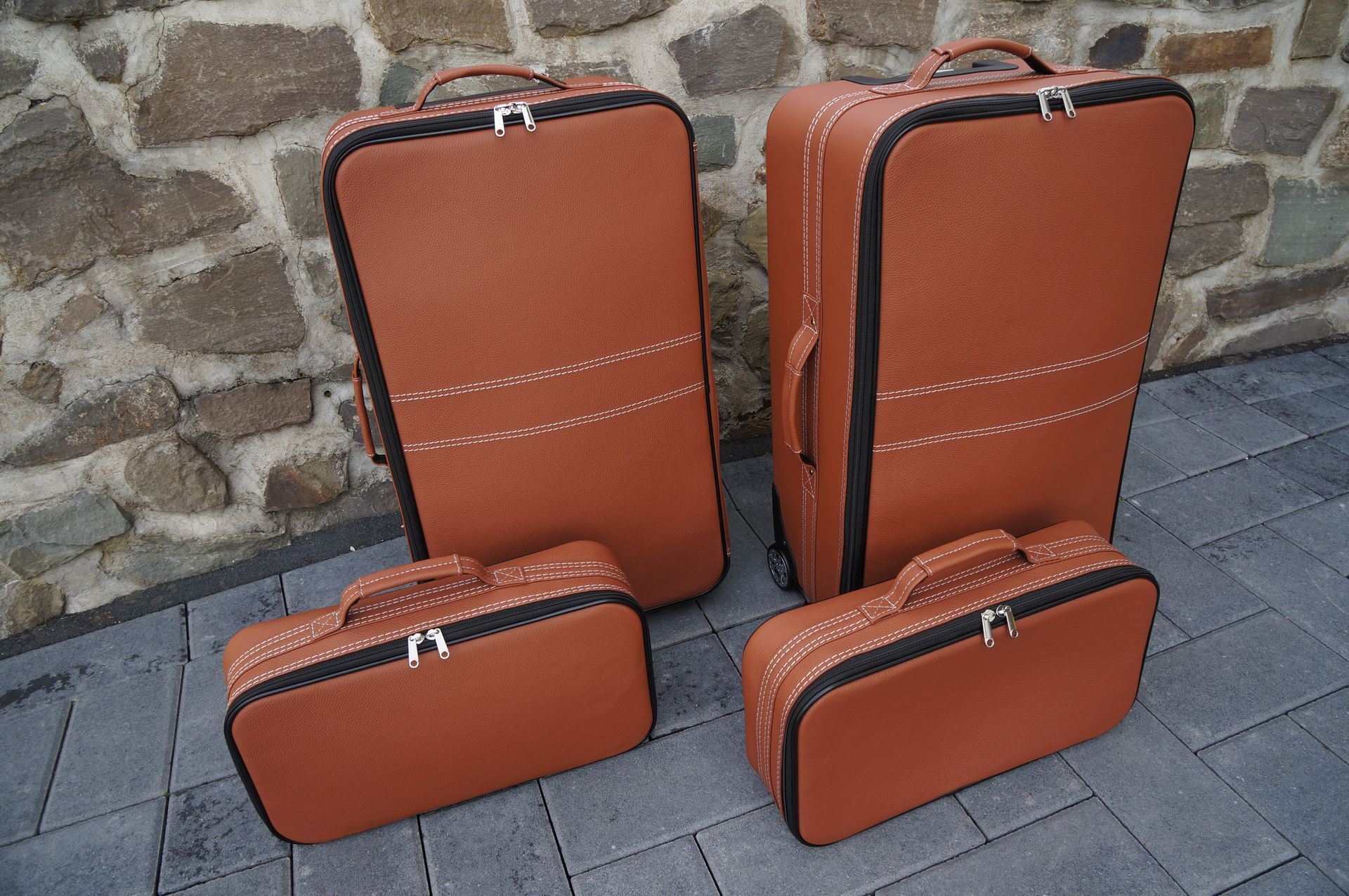 Vier bruine koffers staan ​​op de stoep voor een stenen muur.