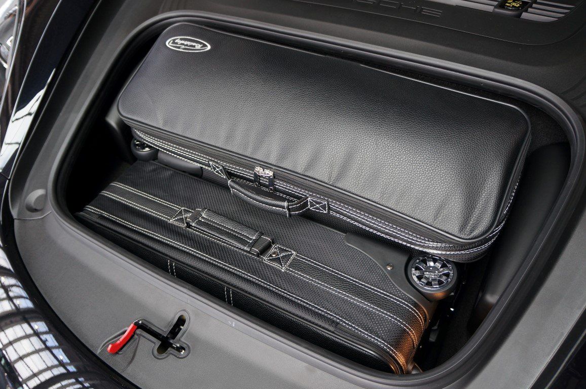 Een zwarte tas ligt in de kofferbak van een auto.