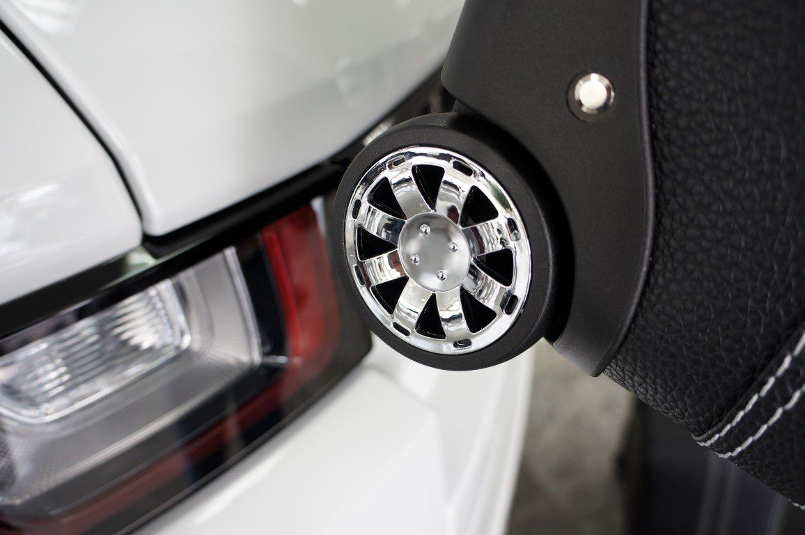 Een close-up van een wiel van een koffer naast een auto.