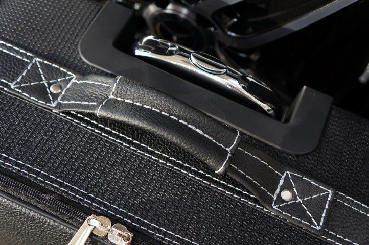 Een close-up van een zwarte koffer met witte stiksels