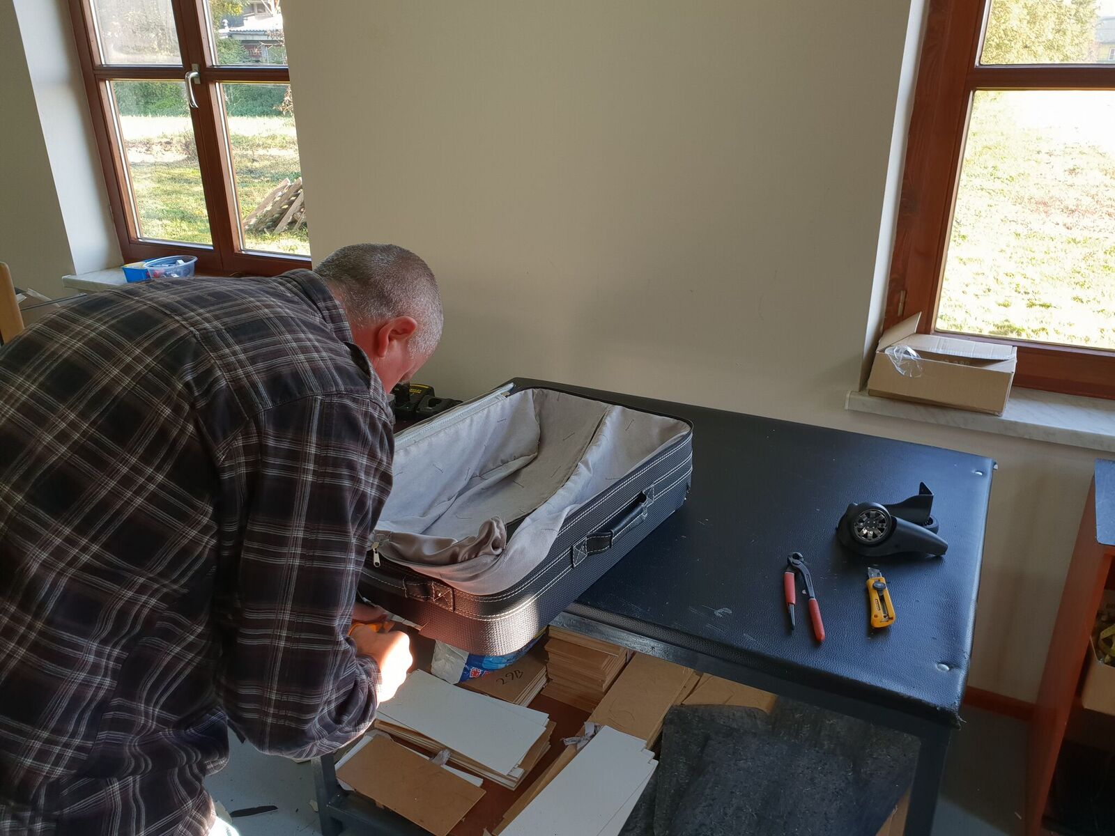 Een man in een geruit overhemd werkt aan een koffer