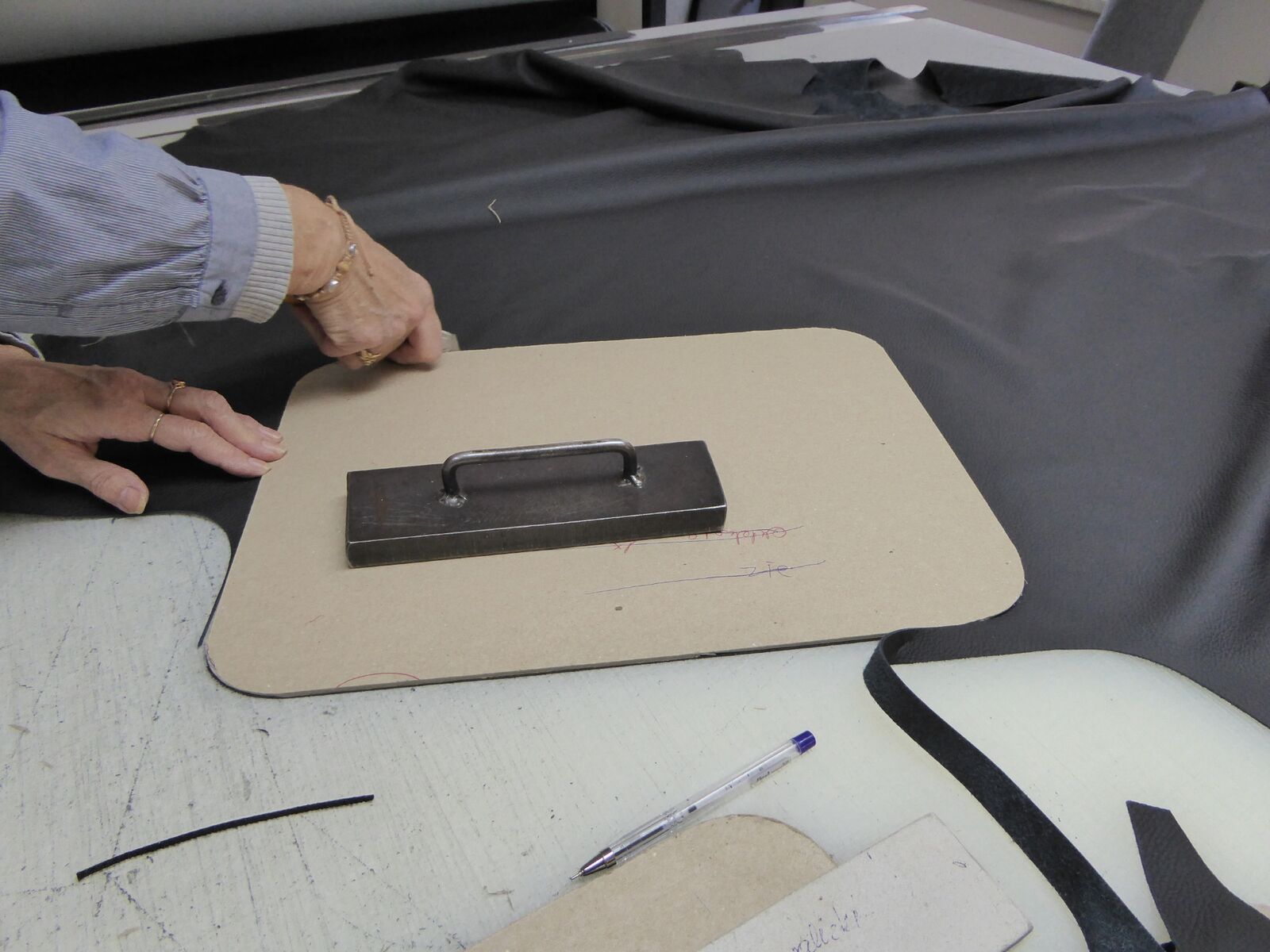 Iemand snijdt een stuk leer op een tafel