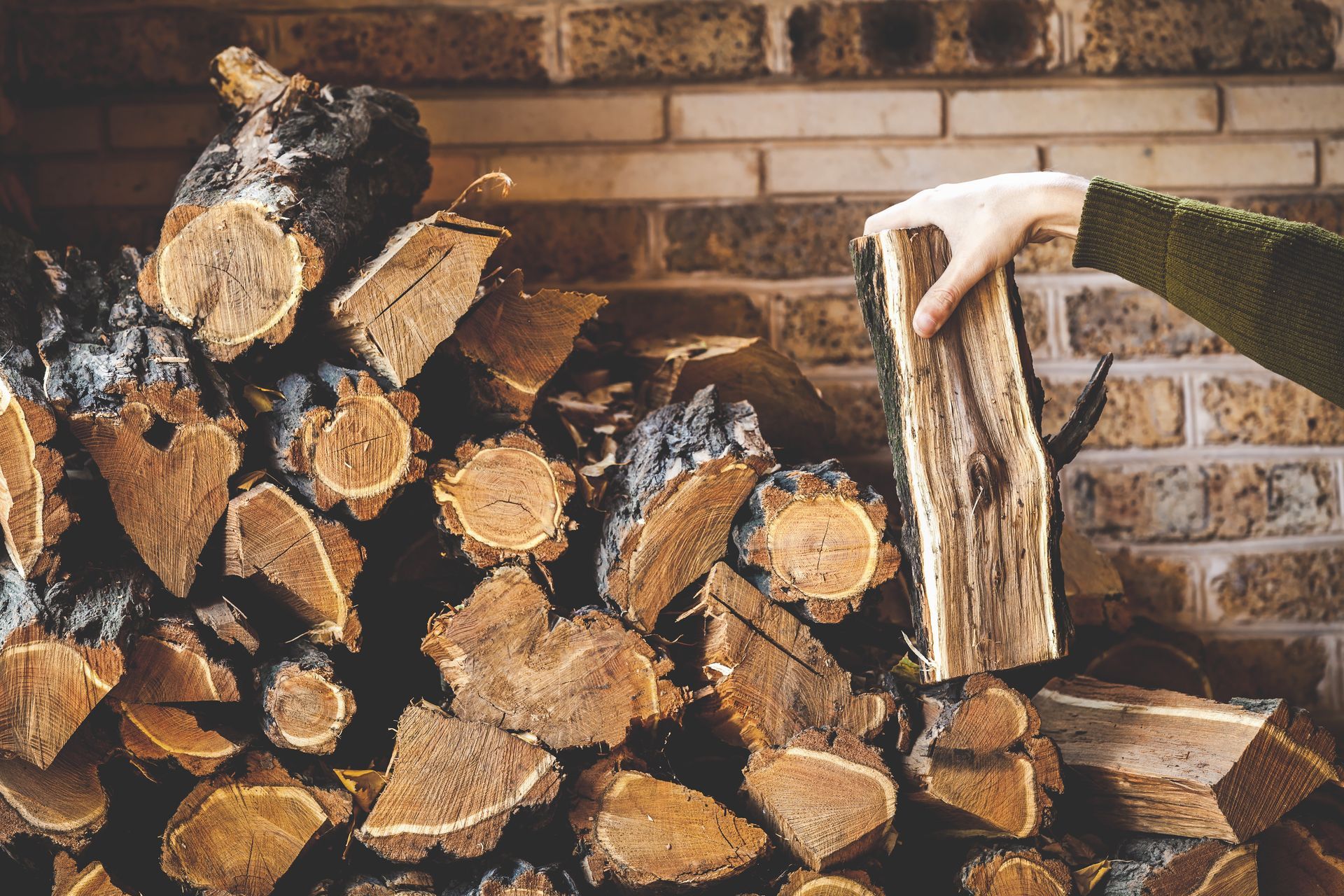 Stacked firewood against a brick wall, with an axe embedded in a log in front. Stacked firewood against a brick wall, with an axe embedded in a log in front.