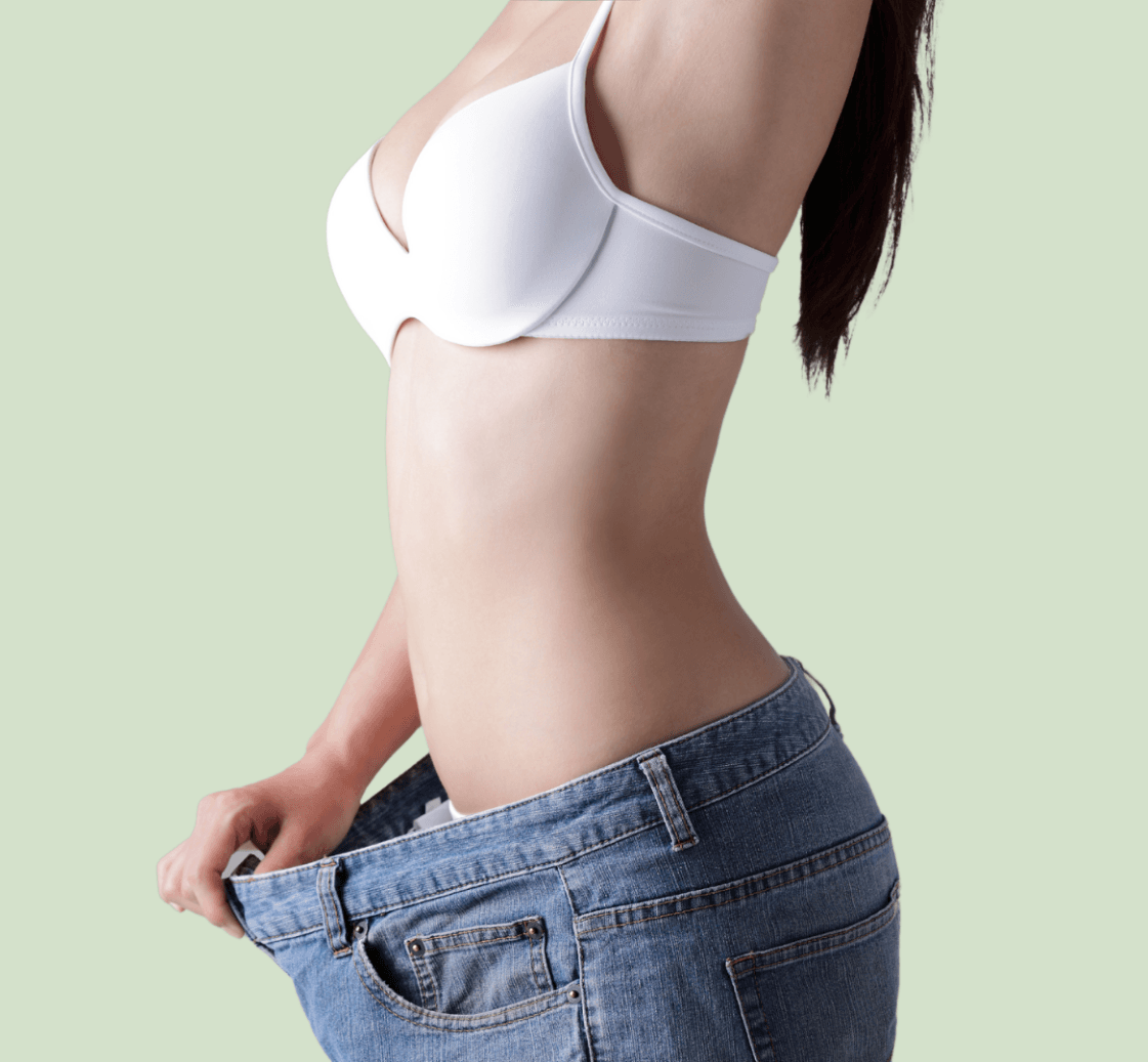 A woman in a white bra and blue jeans is showing off her weight loss