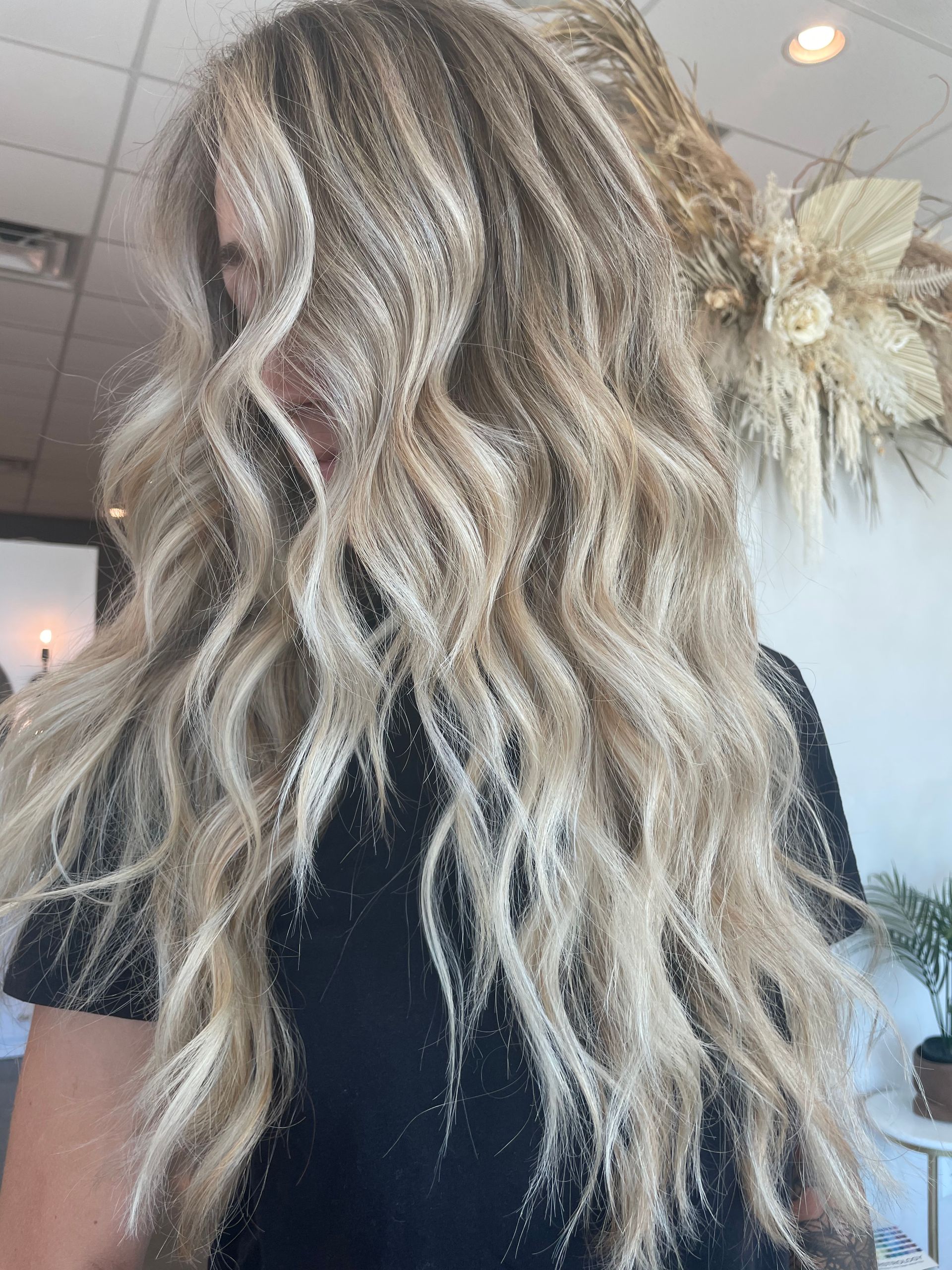 Woman with long, wavy blonde hair; wearing a black shirt.