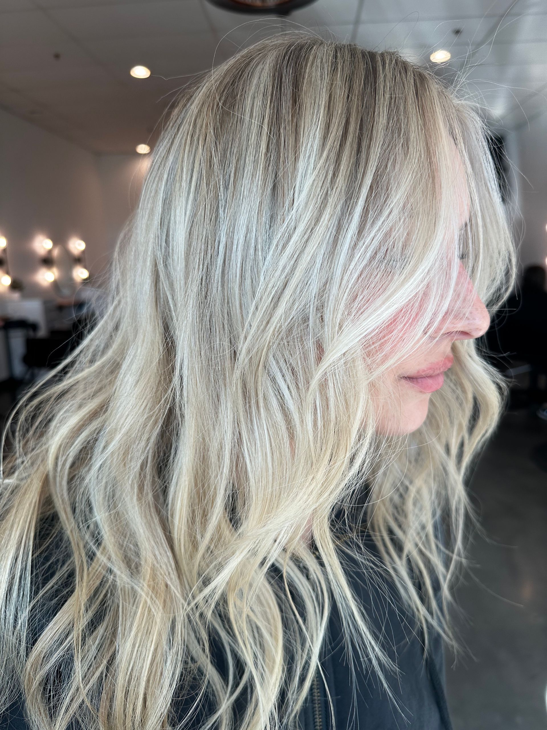 Blonde wavy hair, salon setting, partially covering face.