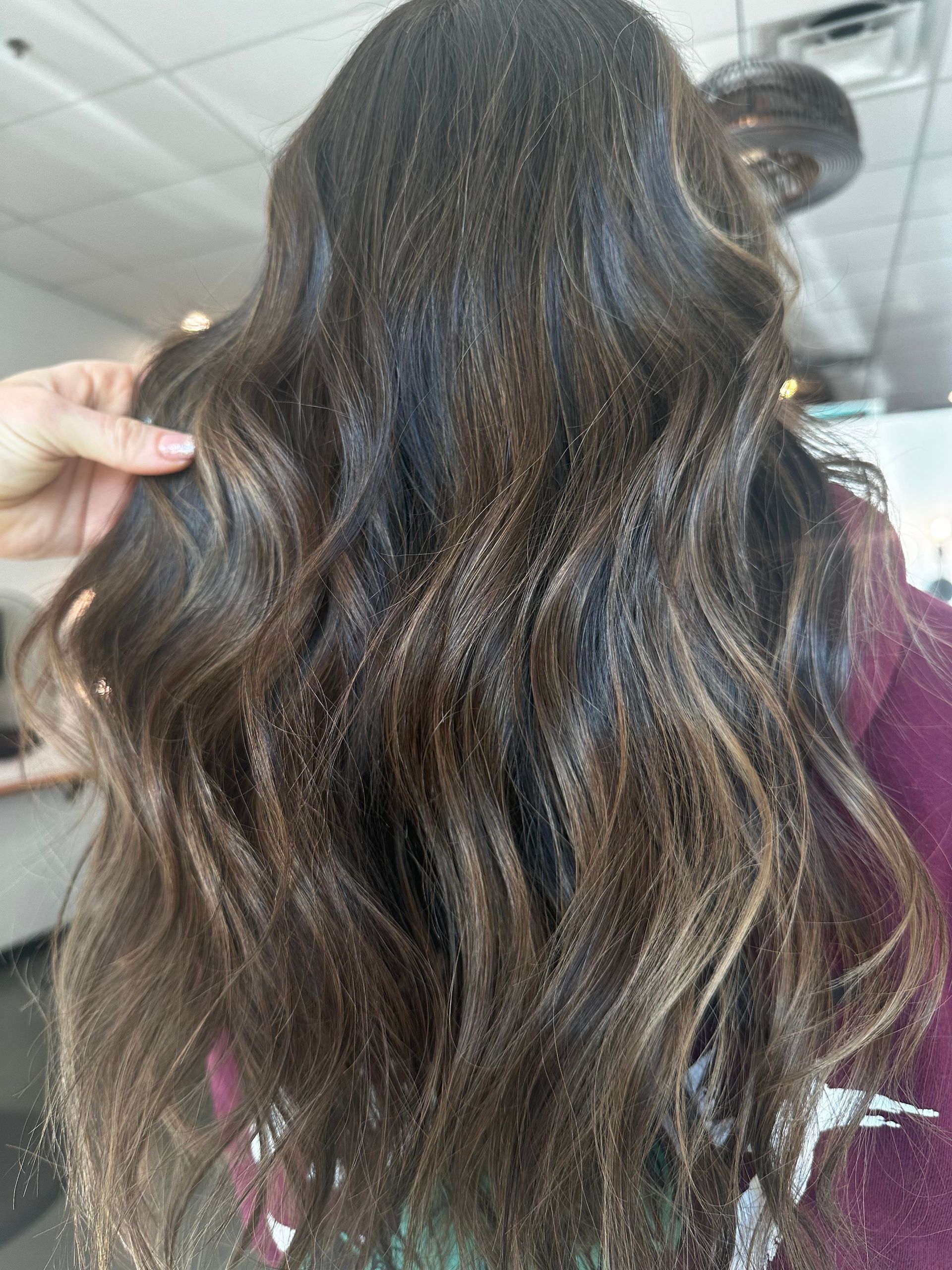 Long, wavy brown hair with highlights, possibly styled at a salon.
