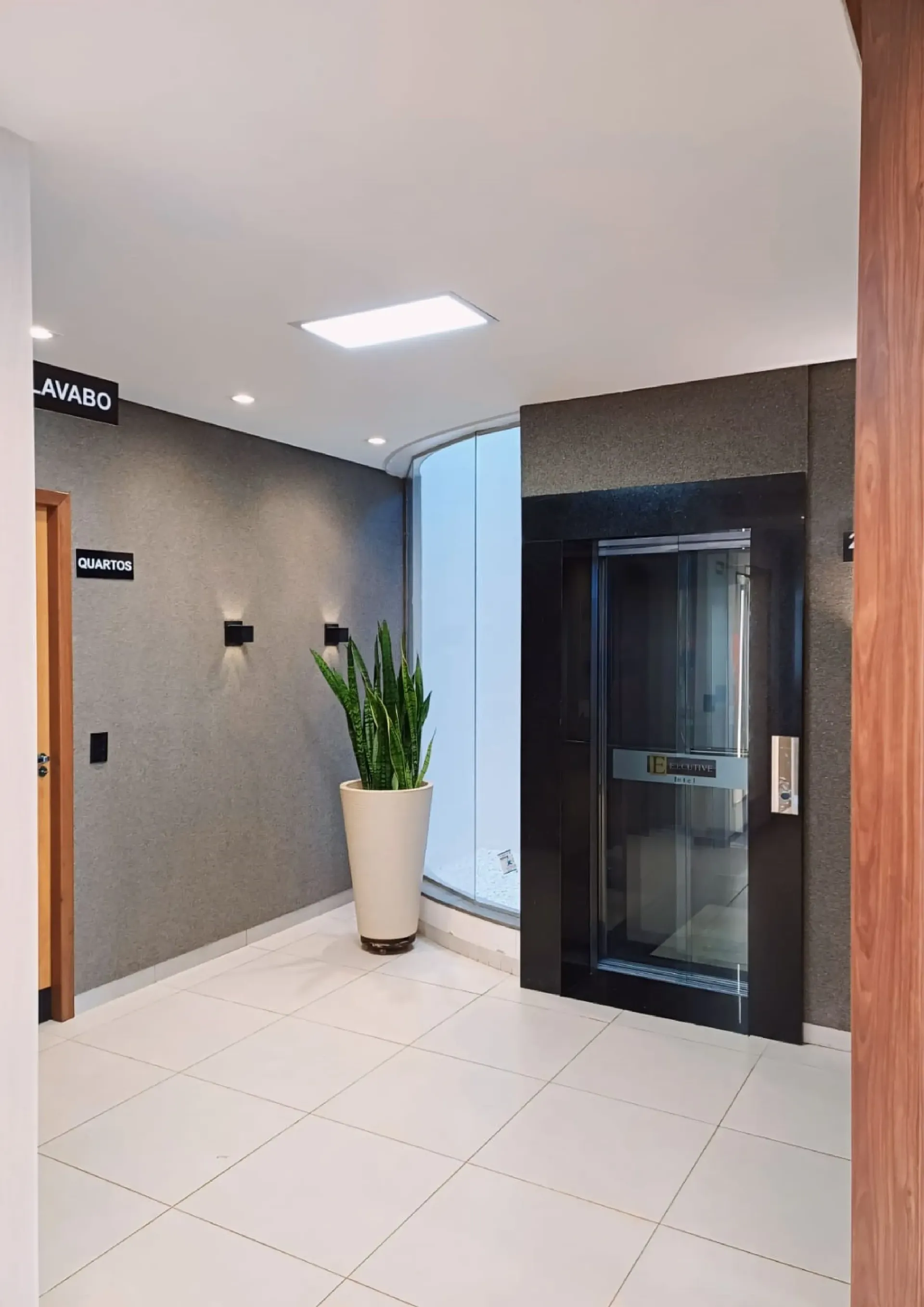 Um corredor com um elevador e uma planta em vaso.-Executive-Hotel-MT
