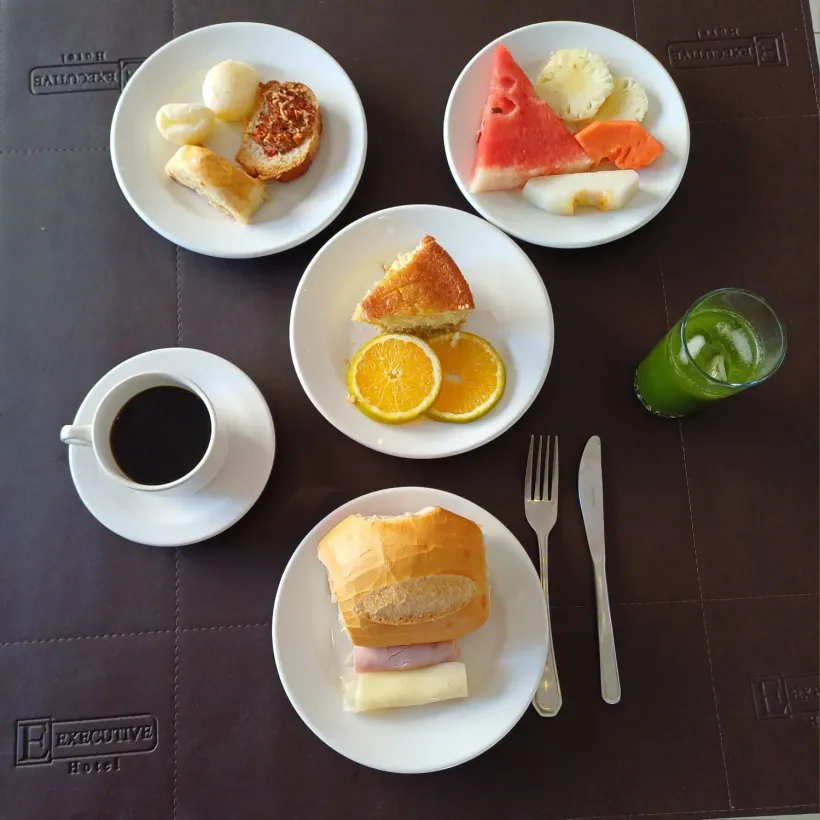 Uma mesa com pratos de comida e uma xícara de café-Executive-Hotel-MT lucas-do-rio-verde