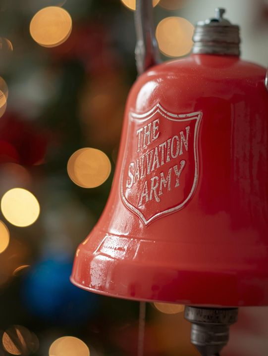 Salvation Army bell ringers standing beside a red kettle during the holiday season.