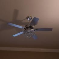 A modern silver ceiling fan with a circular crystal chandelier light fixture mounted on a light-colored ceiling.