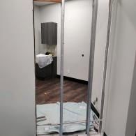 A metal door frame studs opening in a room under construction, with a dark cabinet and protective floor sheeting visible.