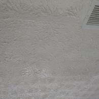 White ceiling with a subtle, raised floral texture and a corner air vent visible.