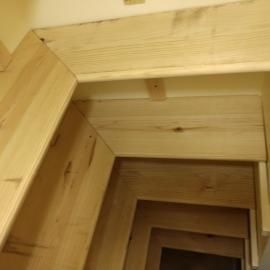 A doorway or hallway framed with unfinished light-colored wood panels and molding.