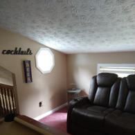 A cozy lounge with a leather recliner, a light-colored ceiling, and wall decor reading 