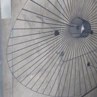 A modern black wire pendant lamp suspended from a textured, light-colored ceiling.