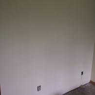A plain, light-colored interior wall with two electrical outlets, one near the floor and one slightly higher on the right.