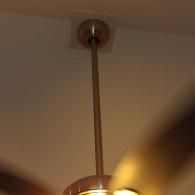 A downward-facing perspective of a metal ceiling fan rod and canopy attached to a white ceiling.