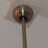 A ceiling fan's metal canopy and downrod secured against a white ceiling.