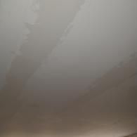 Water stains with irregular dark patterns spreading across a plain, light-colored ceiling.