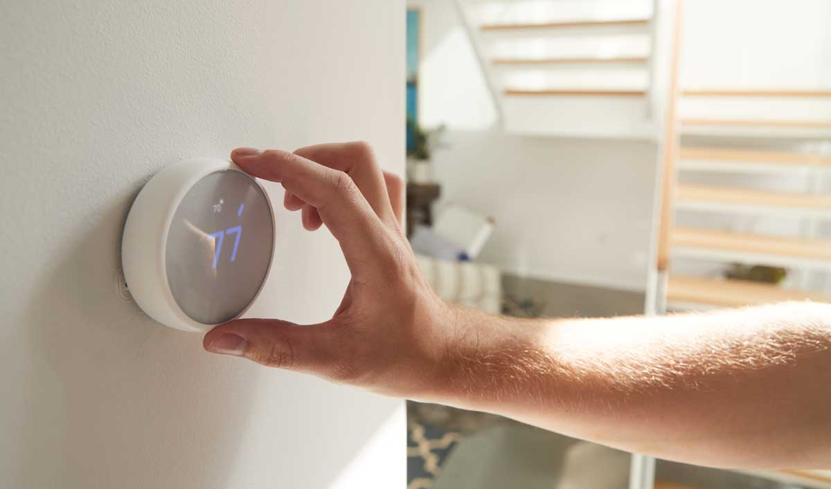 A person is adjusting a thermostat on a wall.