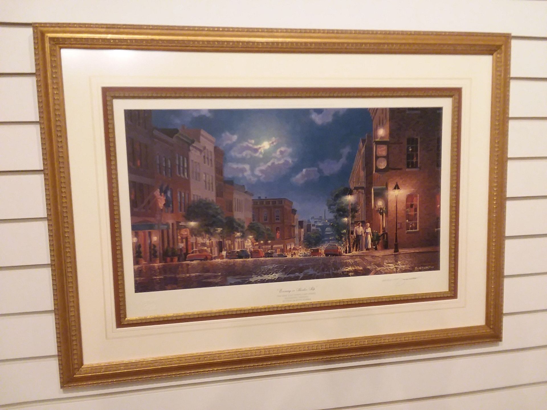 A framed painting of a city street at night