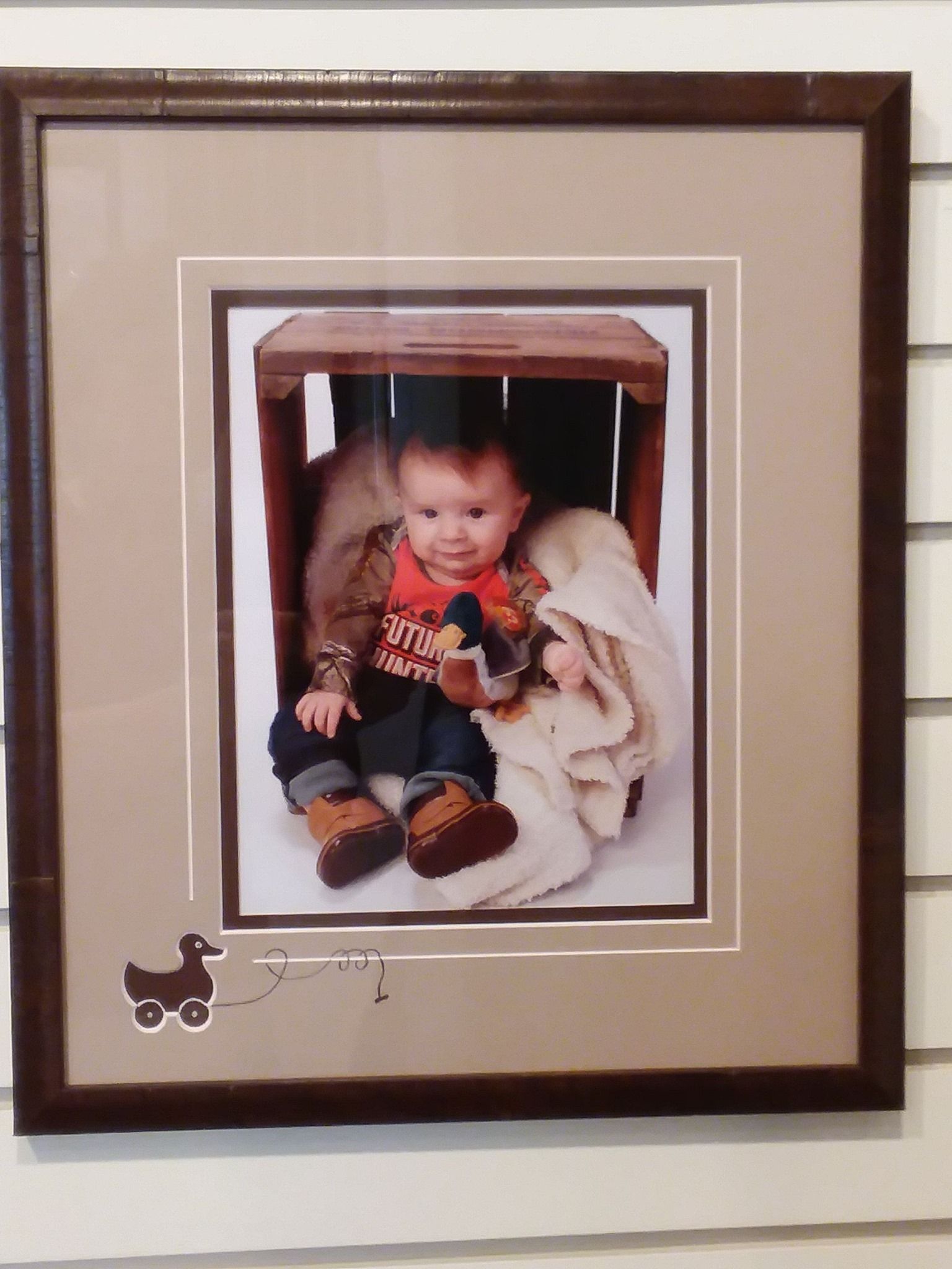A framed picture of a baby sitting under a table