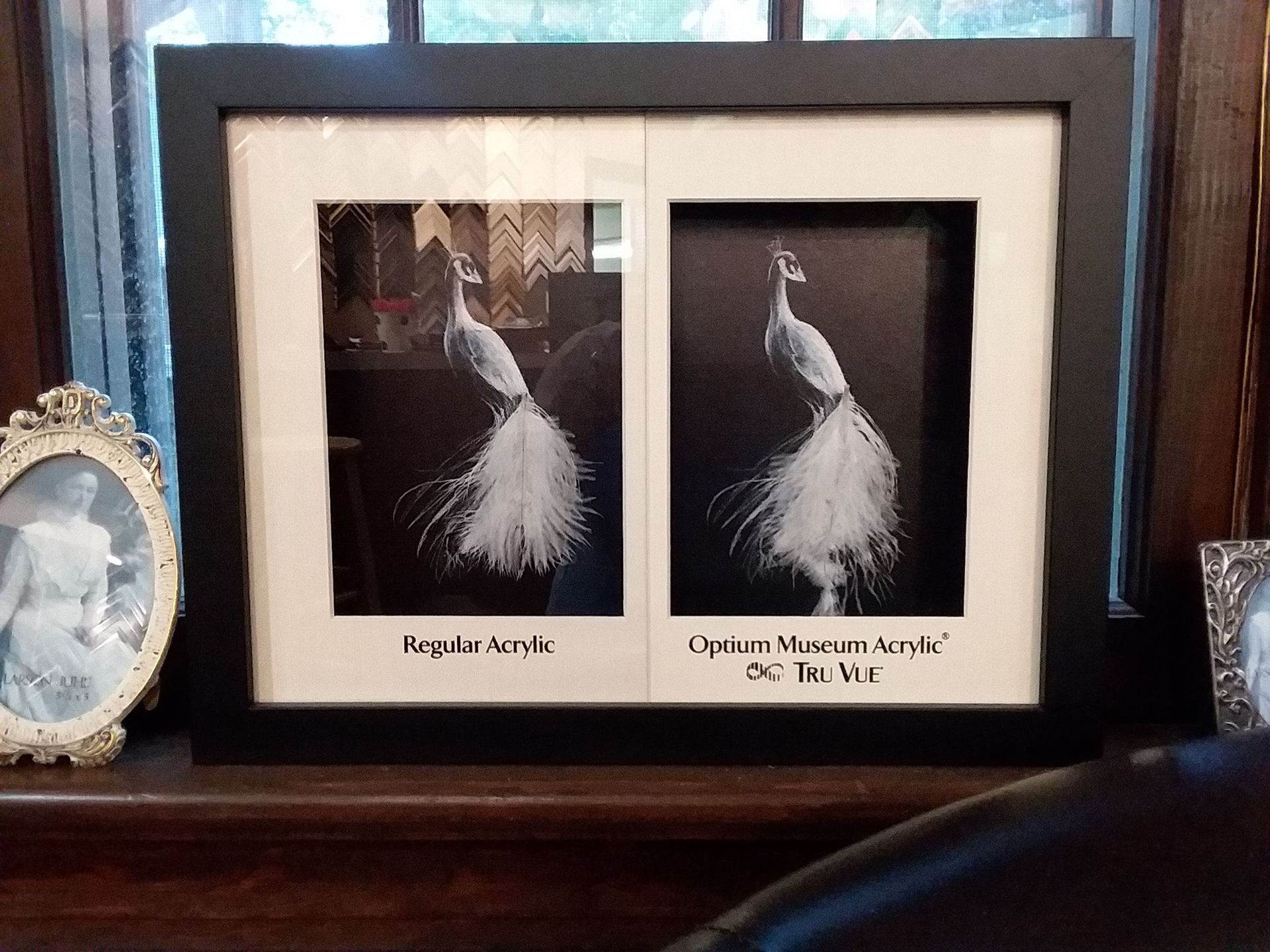 A picture of a peacock is framed in a black frame