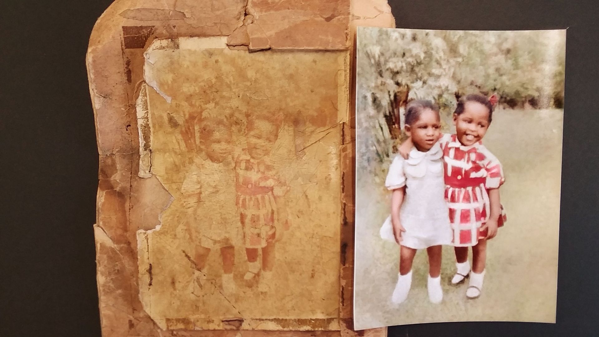 Two little girls are standing next to each other on a piece of paper