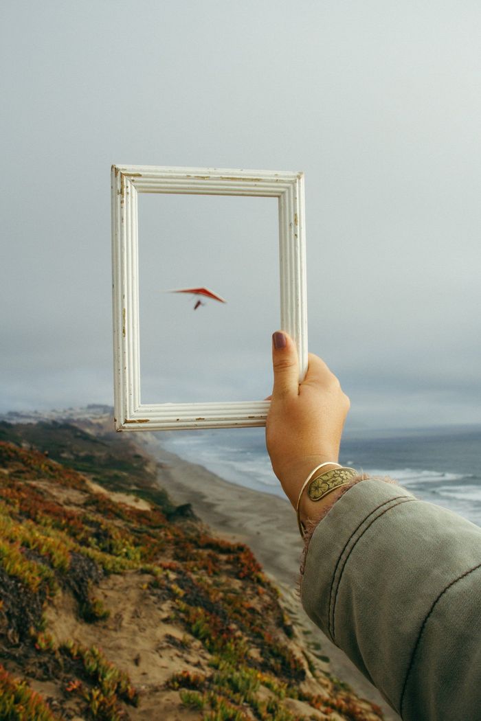 A person is holding a picture frame with a paraglider in it