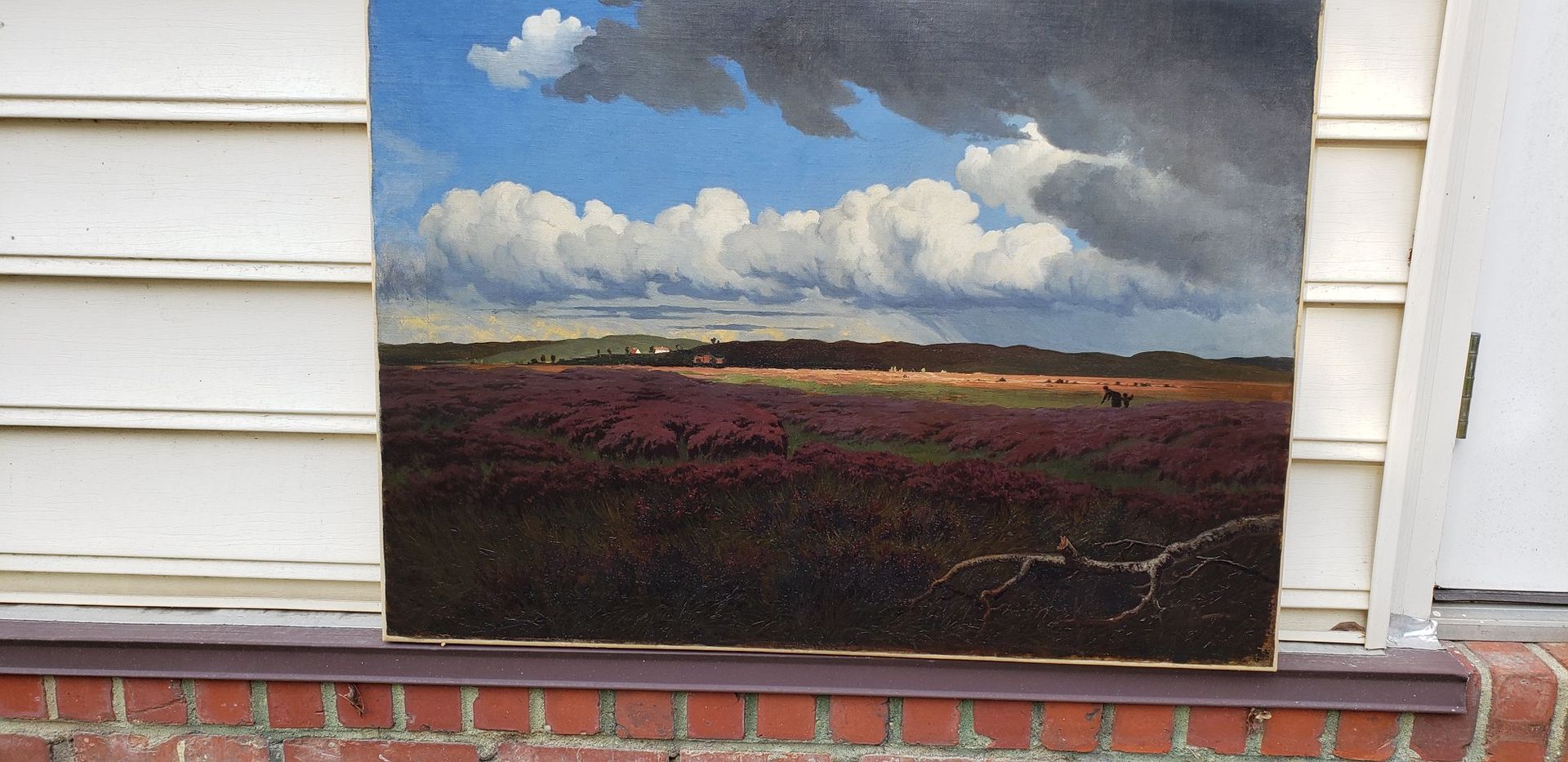 A painting of a field with clouds in the sky