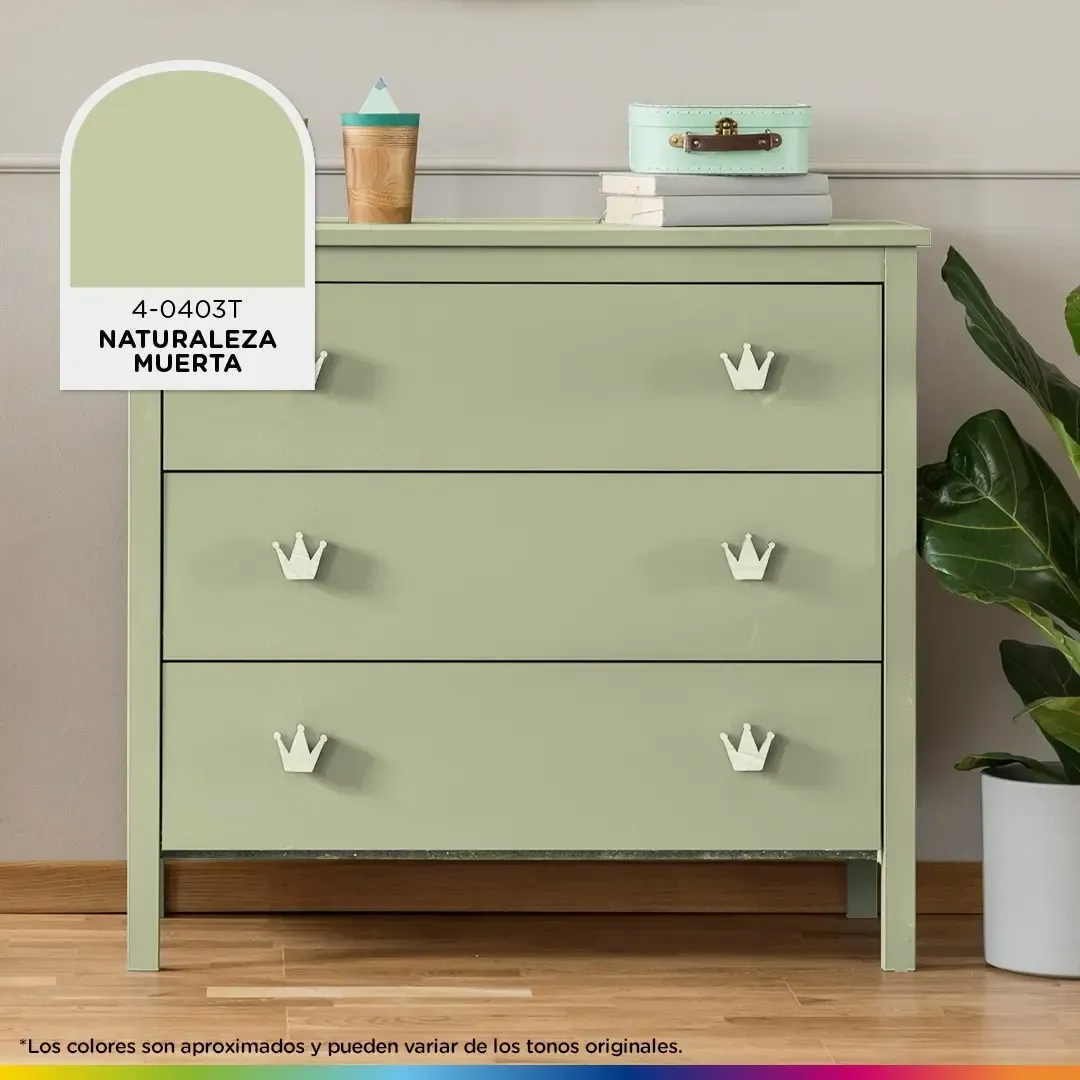 Una cómoda verde con tiradores de corona está situada junto a una planta.