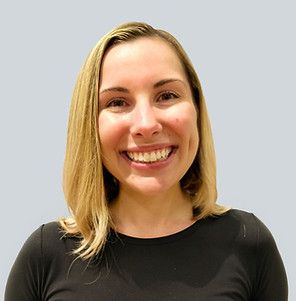 A person with blonde hair and a warm smile, wearing a black shirt against a plain, light-colored background.