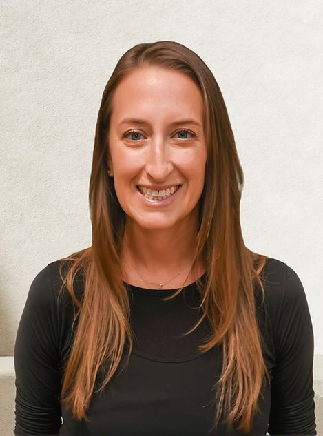 A person with long, center-parted brown hair smiling against a textured, light-colored background.